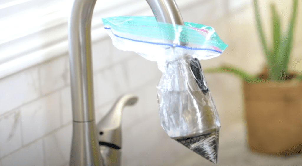 Add remainder of vinegar to zipper lock bag and tie it up with the faucet head soaked inside the bag