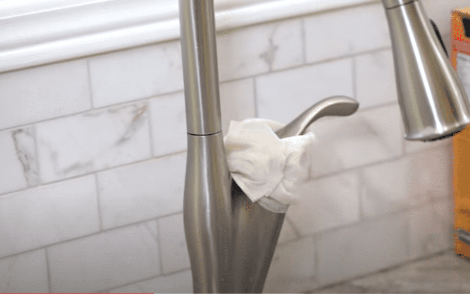 Wrap a paper towel with white vinegar around the faucet